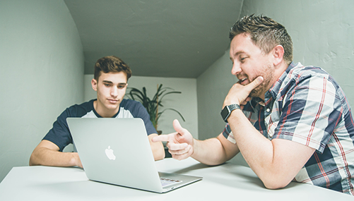 a man and his son looking at a car title loan site on computer 501x285